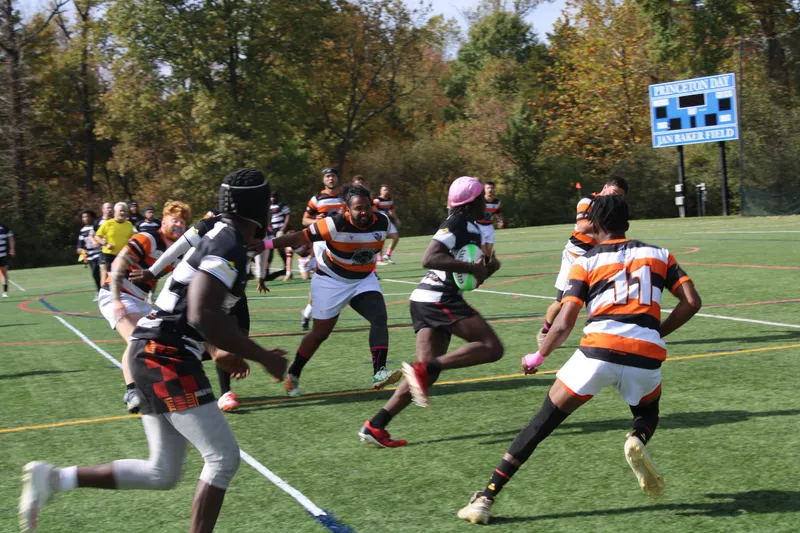A Lions ball carrier attacks the line against a side in orange hoops