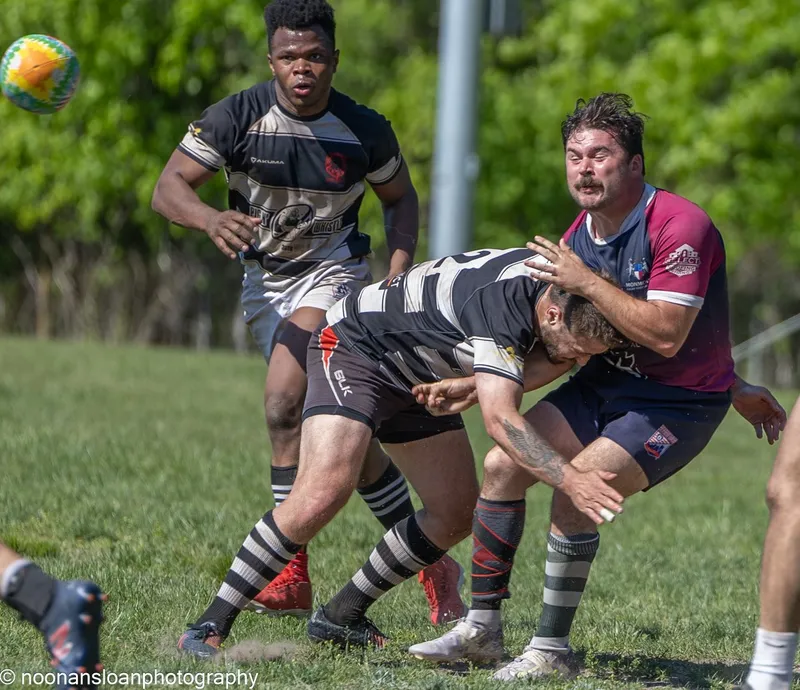 A Lions ball carrier is wrapped up by a defender in maroon